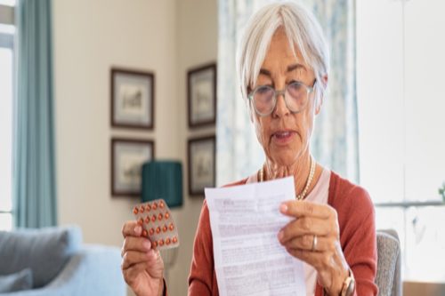 Mãos segurando cartela de comprimidos e instruções impressas