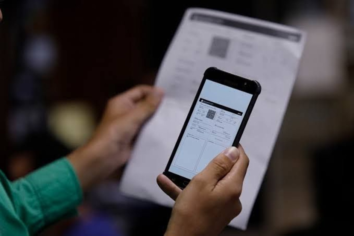 Pessoa compara informações no celular e no papel