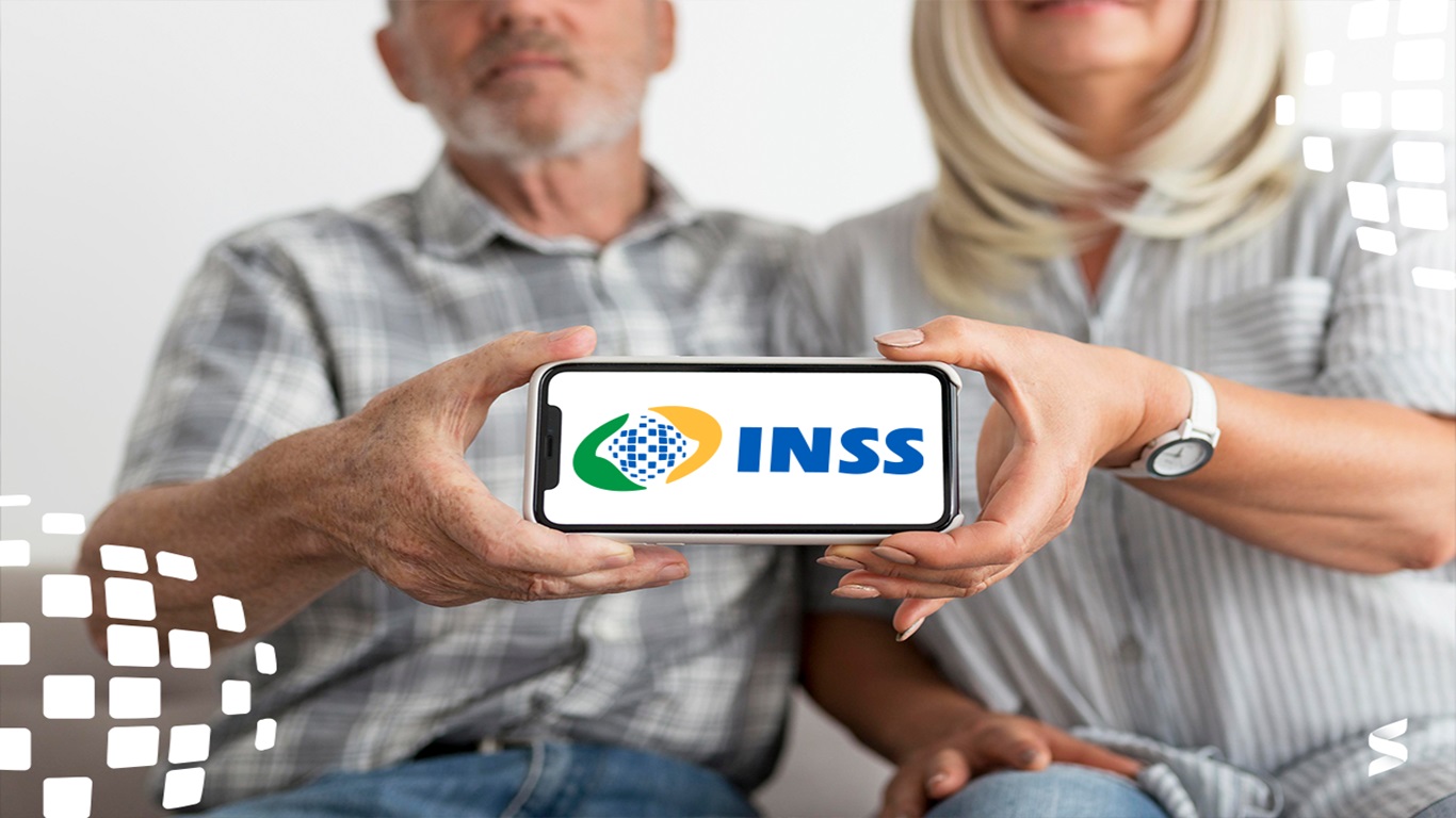 Casal idoso segurando smartphone com o logo do INSS na tela.