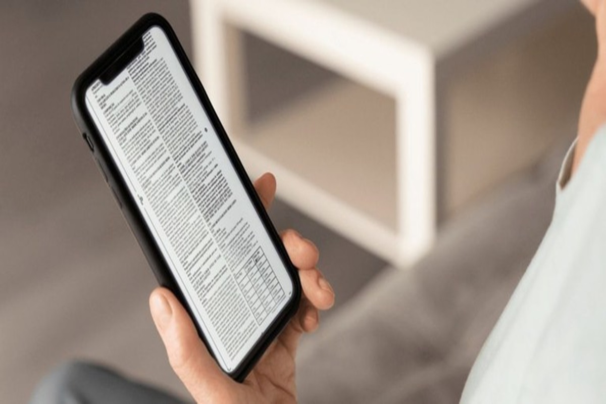 Smartphone exibindo um texto longo com uma tabela na tela.
