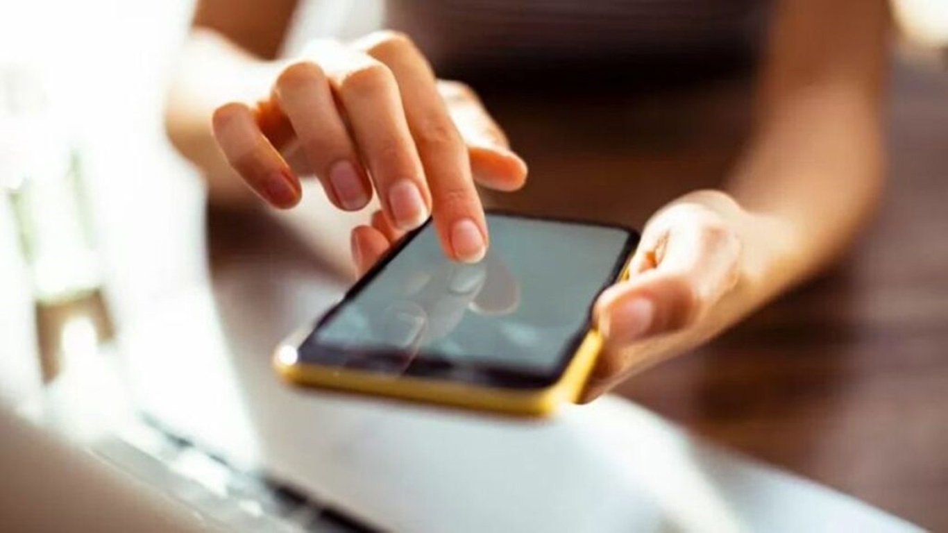Pessoa segurando um smartphone com capa vibrante e interagindo com a tela.
