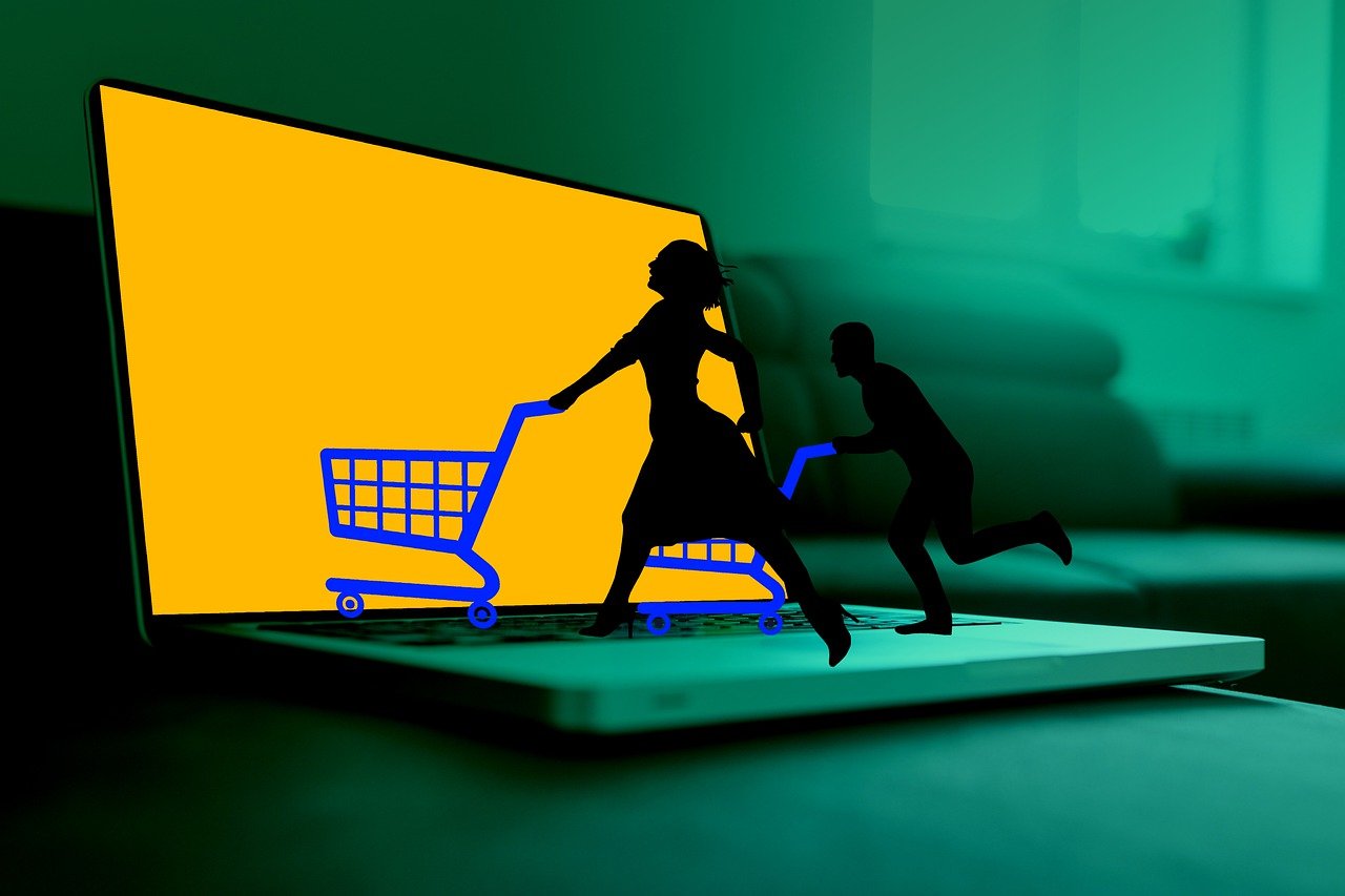 Representação conceitual de compras online com silhuetas empurrando carrinhos de compras saindo de uma tela de notebook, simbolizando a experiência de anunciar no Instagram Shopping.